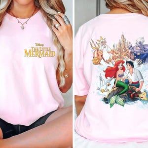May include: Pink t-shirt with a gold "Disney The Little Mermaid" graphic on the front and a colorful graphic of Ariel, Prince Eric, King Triton, Ursula, and a castle on the back.