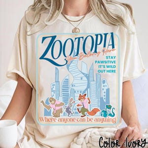 Puede incluir: Camiseta de color marfil con un gr&aacute;fico de la pel&iacute;cula Zootopia. El dise&ntilde;o incluye el t&iacute;tulo, los personajes y la frase "Where anyone can be anything". La camiseta tiene cuello redondo y mangas cortas.
