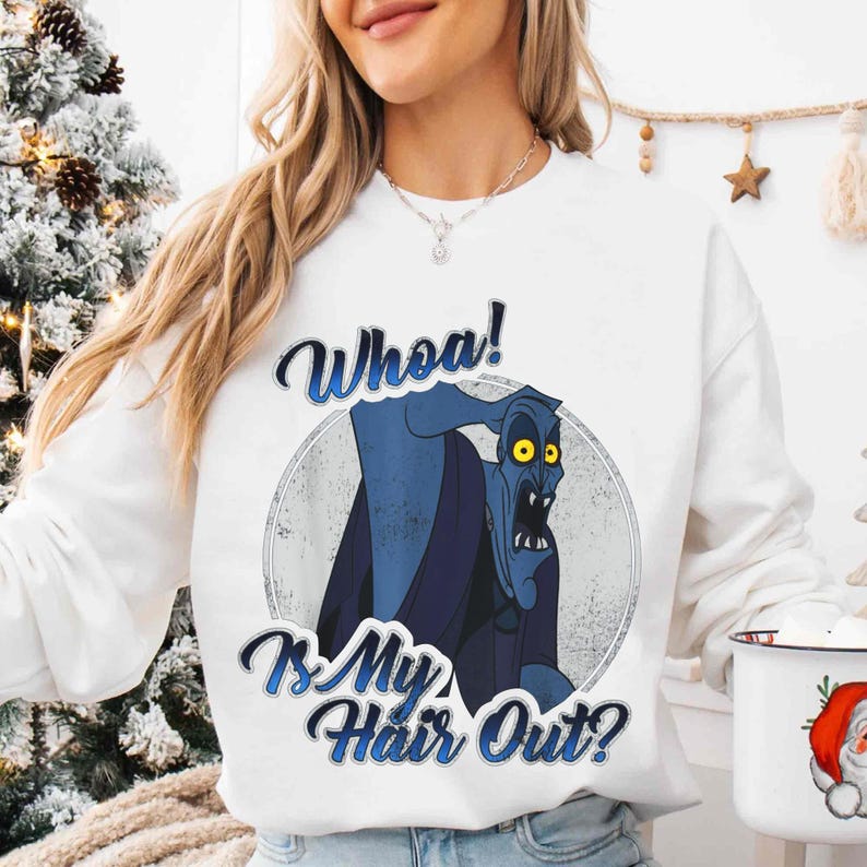 Puede incluir: Sudadera blanca con una ilustraci&oacute;n de dibujos animados de un personaje azul con ojos amarillos y el texto "Whoa! Is My Hair Out?" en una fuente azul estilizada. El dise&ntilde;o est&aacute; dentro de un c&iacute;rculo gris.