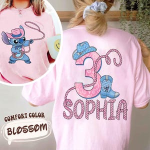 May include: Pink Comfort Color t-shirt with a cartoon Stitch character wearing a cowboy hat and holding a lasso. The back features a pink number 3, a cowboy hat, a boot, and the name "Sophia" in a rope-like font.
