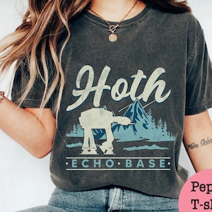 May include: A dark gray t-shirt with a vintage-style graphic of an AT-AT walker in a snowy landscape. The graphic includes the text "Hoth Echo Base".