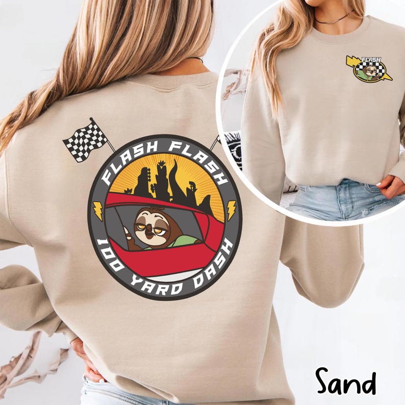 May include: Sand-colored sweatshirt with a graphic of a sloth in a race car, the text "Flash Flash 100 Yard Dash", and a checkered flag. The design is repeated on the front. The word "Sand" is printed at the bottom.