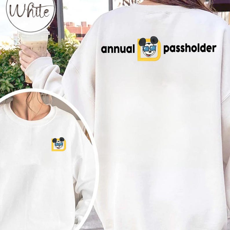 Puede incluir: Sudadera blanca con la frase "annual passholder" y un dibujo animado de un rat&oacute;n con gafas de sol. El dibujo est&aacute; dentro de un cuadrado amarillo. Una versi&oacute;n m&aacute;s peque&ntilde;a del dibujo est&aacute; en la parte delantera.