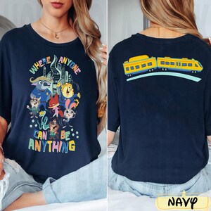 Pu&ograve; includere: T-shirt blu navy con una grafica colorata con personaggi dei cartoni animati e la scritta "WHERE ANYONE CAN BE ANYTHING". Il retro della maglietta mostra un disegno di un treno giallo. La parola "NAVY" &egrave; in basso.