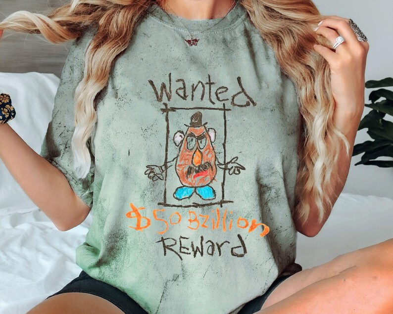 K&ouml;nnte beinhalten: Gr&uuml;nfarbenes T-Shirt mit Batik-Muster und einer Comic-Zeichnung von Mr. Potato Head mit dem Text "Wanted 50 Milliarden Dollar Belohnung".