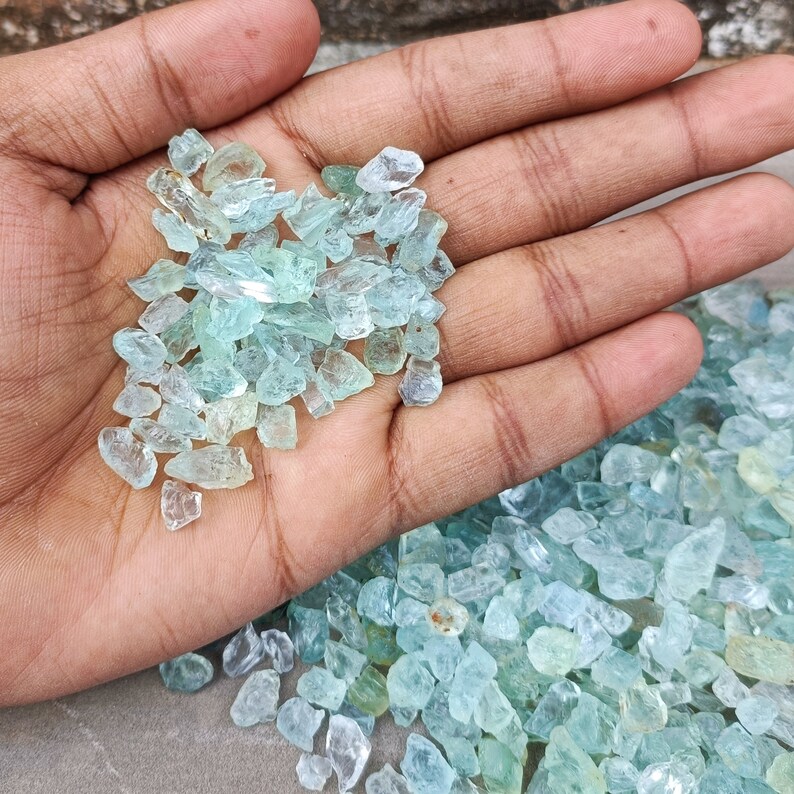 Puede incluir: Un pu&ntilde;ado de piedras preciosas de aguamarina azul claro, con un mont&oacute;n m&aacute;s grande de las mismas piedras en el fondo.