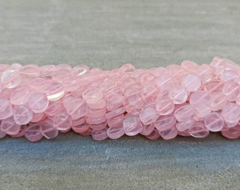 May include: A strand of pale pink, translucent, round, faceted gemstone beads. The beads are slightly irregular in shape and have a smooth, polished finish.