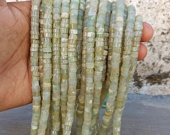 May include: A strand of light green gemstone beads, each bead is square shaped with rounded edges. The beads are strung on a clear thread and are approximately 6mm in size.