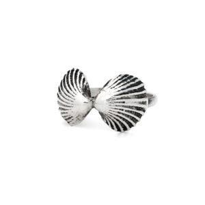 Peut inclure: Bague argentée représentant un nœud papillon. Le nœud est composé de deux éléments en forme de coquillage avec des textures striées détaillées. La bague est posée sur un fond blanc uni, mettant en valeur le design du bijou.
