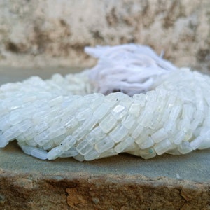 May include: A strand of white moonstone beads, each bead is a rectangular shape with a smooth, polished finish.
