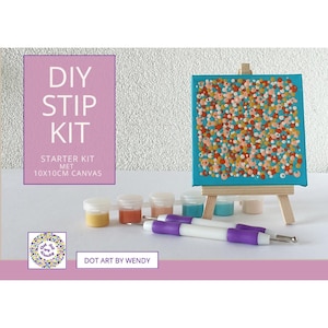 Può includere: Un kit fai-da-te per l'arte dei puntini con una tela turchese con un design a puntini colorati. Il kit include vasetti di vernice, strumenti per puntini e un piccolo cavalletto di legno. Il testo sulla scatola recita "DIY STIP KIT".