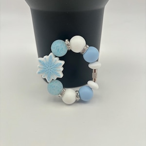 May include: A blue and white beaded bracelet with a snowflake charm. The bracelet has a silver clasp.