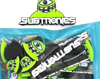 May include: A selection of Subtronics-branded accessories. The accessories feature a neon green monster eye design with the word "Subtronics" in white. The accessories are black and neon green. The package is light blue.