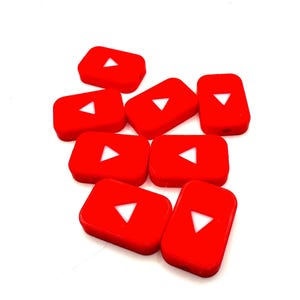 May include: Eight red plastic buttons with a white play button symbol on each. The buttons are arranged in a pile.