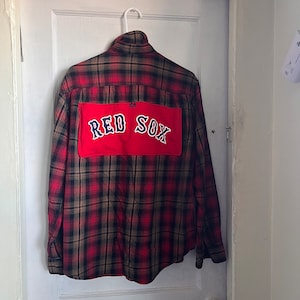 May include: Red and black plaid flannel shirt with a red patch on the back that says "RED SOX" in white lettering.