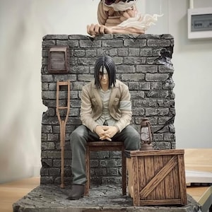 Puede incluir: Estatua detallada de Eren Yeager de la serie de anime Ataque a los Titanes, con una figura de Titán sobre una pared de ladrillo. Incluye una caja de madera, una linterna y una muleta. La base tiene el texto 'EREN YEAGER'.
