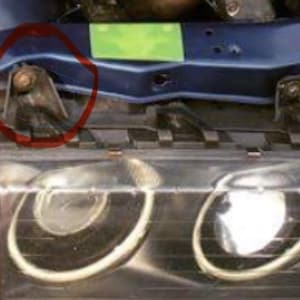 Peut inclure: Gros plan sur le compartiment moteur d'une voiture bleue, montrant une charnière métallique avec un joint en caoutchouc noir. Les phares de la voiture sont visibles au premier plan.
