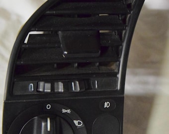 May include: Black plastic car dashboard switch with a round knob, a vent, and several buttons. The knob has symbols for headlights, fog lights, and parking lights. The buttons have symbols for headlights, fog lights, and parking lights.