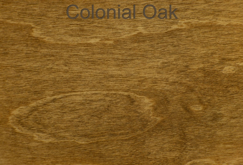 Pode incluir: Close-up de um padr&atilde;o de gr&atilde;o de madeira com um tom castanho-dourado quente. O texto "Colonial Oak" &eacute; exibido no topo. O gr&atilde;o da madeira apresenta um design natural e fluido, mostrando a textura e as varia&ccedil;&otilde;es de cor.
