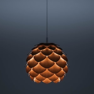 May include: A wooden pendant light with a layered shade. The shade is made of overlapping, leaf-shaped pieces, forming a textured sphere. The light emits a warm glow, highlighting the wood grain. The fixture hangs from a white cord. The light's diameter is approximately 30 cm.