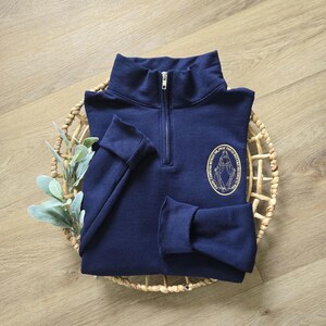 A navy sweatshirt with vegas gold thread for the miraculous medal.