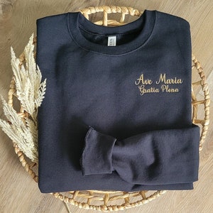 May include: Black sweatshirt with gold embroidery that reads "Ave Maria Gratia Plena".