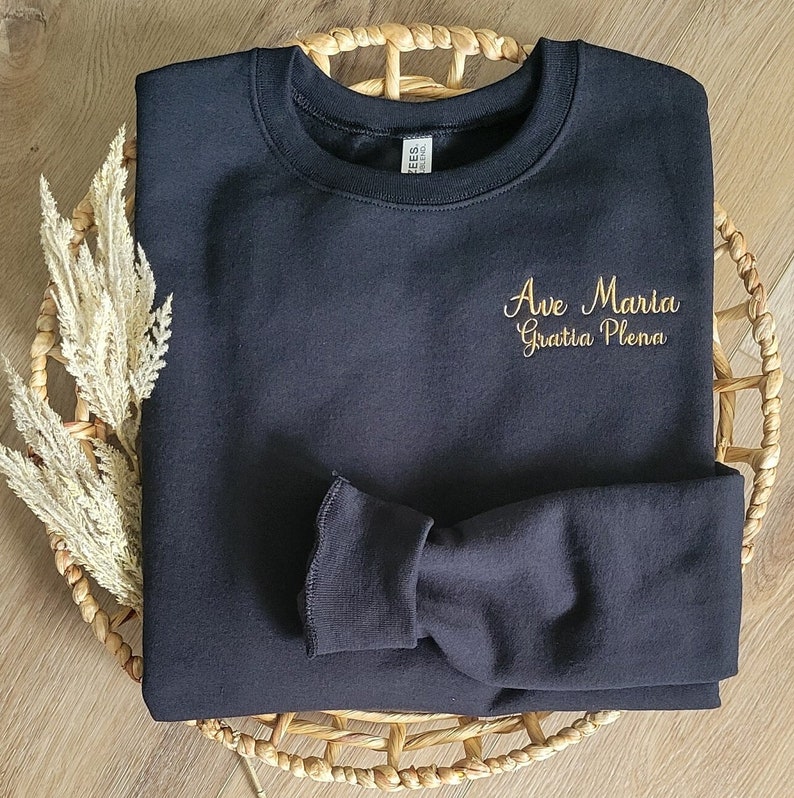 May include: Black sweatshirt with gold embroidery that reads "Ave Maria Gratia Plena".