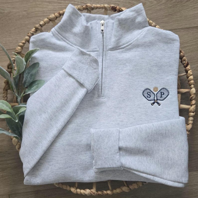 An ash sweatshirt with navy thread for the paddles/initials and caramel thread for the ball.