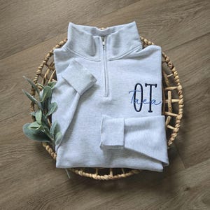 An ash sweatshirt with navy thread for OT and sky blue thread for the name.