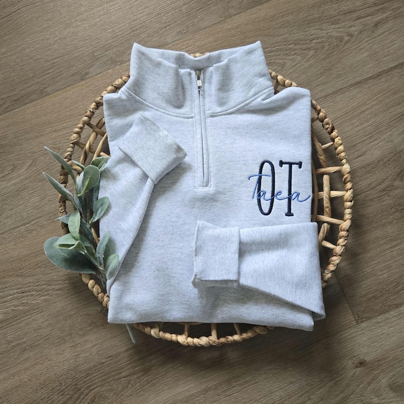 An ash sweatshirt with navy thread for OT and sky blue thread for the name.