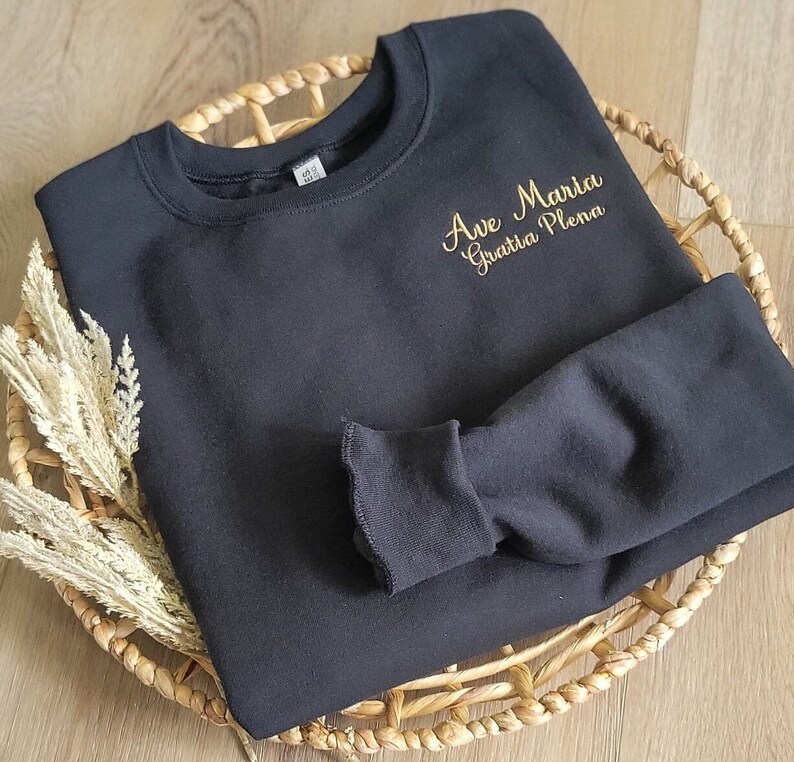 May include: Black sweatshirt with gold embroidery that reads "Ave Maria Gratia Plena".
