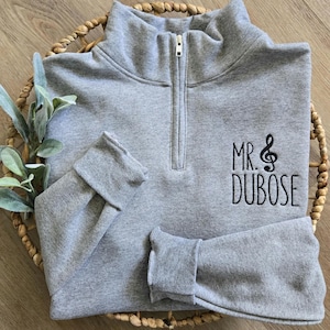 An oxford sweatshirt with black thread for the treble clef and name.
