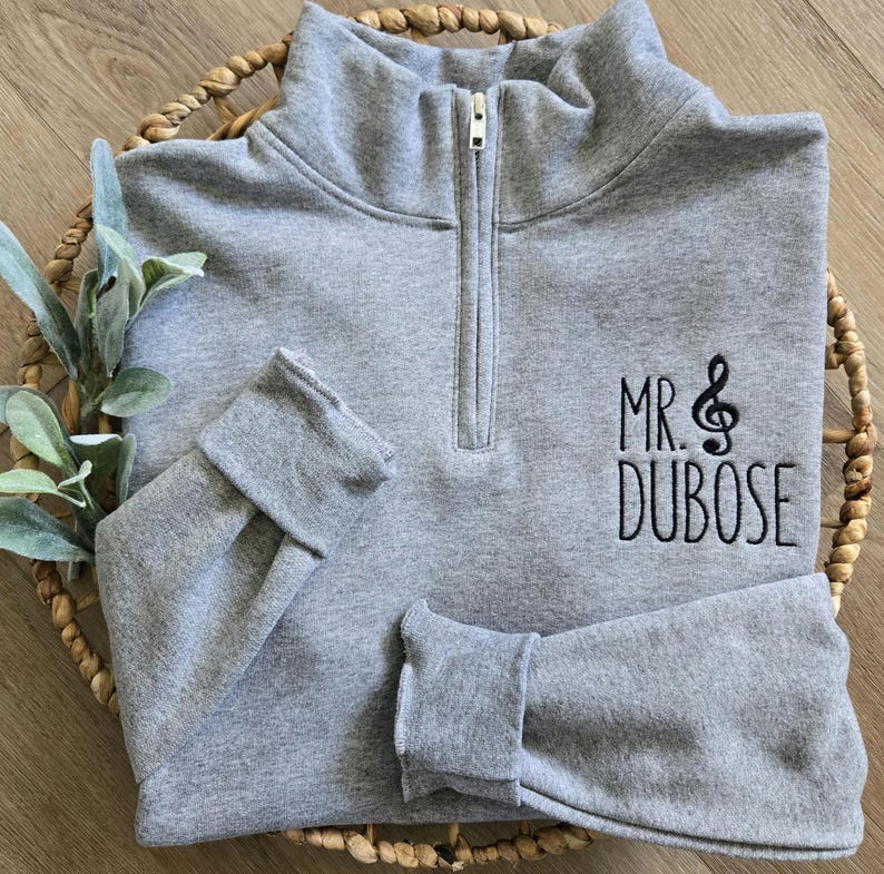An oxford sweatshirt with black thread for the treble clef and name.