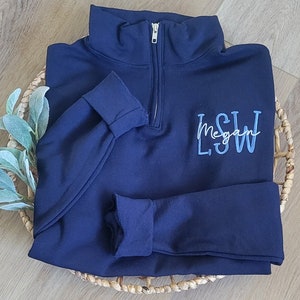 May include: A navy blue quarter-zip sweatshirt with a blue embroidered monogram that reads "L.S.W. Megan".