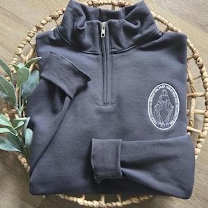 A charcoal greay sweatshirt with white thread for the miraculous medal.