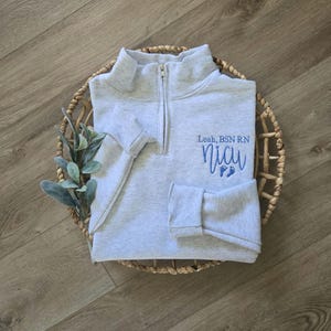 An ash grey sweatshirt with sky blue thread.