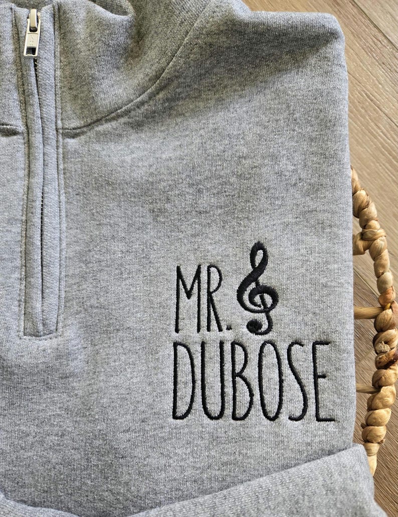 May include: Gray quarter-zip sweatshirt with black embroidered text that reads "MR. & DUBOSE" with a treble clef symbol.