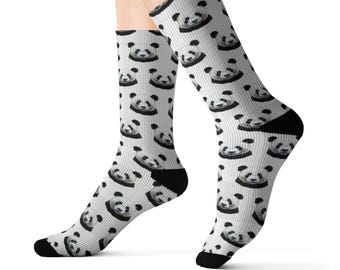 Könnte beinhalten: Ein Paar wadenlange Socken mit einem sich wiederholenden Muster aus Pandagesichtern auf weißem Grund. Die Socken haben einfarbig schwarze Fersen und Zehenbereiche, wobei die Pandagesichter in Schwarz und Weiß ein einheitliches Design bilden.