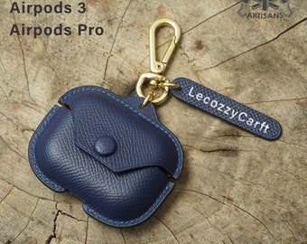 May include: A navy blue leather case with a gold keychain and a tag that reads "LecozzyCarft". The case is designed for AirPods 2, 3, and Pro.