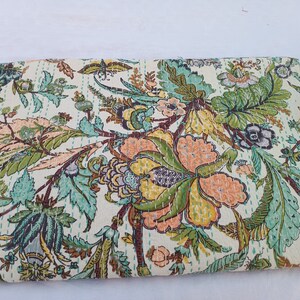May include: Cream-colored textile with a vibrant floral pattern in shades of peach, green, and teal. The design features large flowers and foliage, with visible stitching throughout. This decorative textile is suitable for home decor.