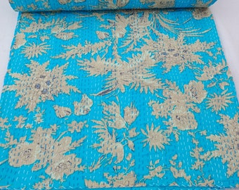 May include: A turquoise blue kantha quilt with a floral pattern in beige. The quilt is folded and rolled up, showing the intricate stitching and design.