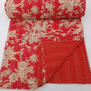 May include: Red kantha quilt with a floral pattern. The quilt is made of cotton and is hand-stitched. It is a traditional Indian textile.