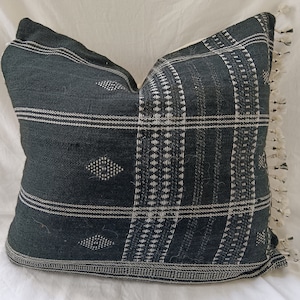 May include: Black and white patterned throw pillow with fringe trim. The pillow is made of a woven fabric with a geometric design.