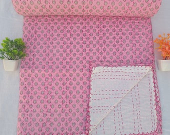 May include: Pink kantha quilt with a white floral pattern. The quilt is folded in half and has a white backing with pink stitching.
