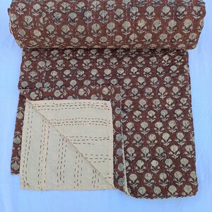 Puede incluir: Un edred&oacute;n marr&oacute;n enrollado con un estampado floral crema. El edred&oacute;n est&aacute; hecho de tela suave y presenta detalles cosidos a mano. La parte inferior es crema con costuras horizontales. Textil decorativo para el hogar.