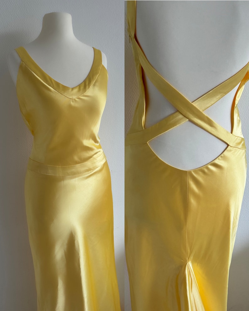 Puede incluir: Un vestido de sat&eacute;n amarillo con un escote en V pronunciado y un dise&ntilde;o de espalda cruzada. El vestido tiene un corpi&ntilde;o ajustado y una falda fluida.