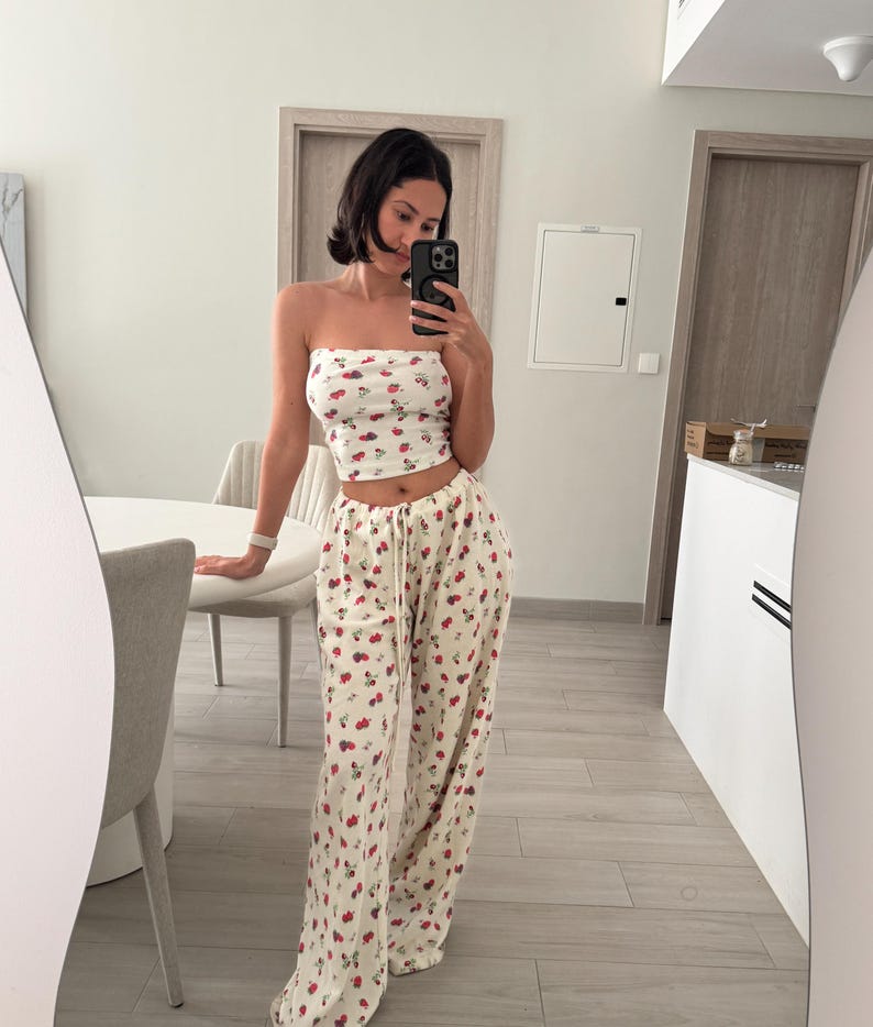 May include: A white crop top with a red and white cherry print and matching wide-leg pants.