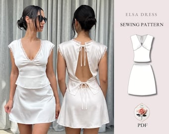 May include: A white satin two-piece set consisting of a sleeveless top with lace trim and a matching skirt. The top features a deep V-neckline and an open back with tie closures. The image includes a technical drawing labeled ELSA DRESS SEWING PATTERN.