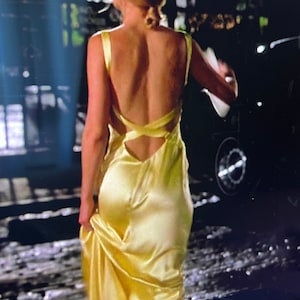 Puede incluir: Una mujer con un vestido de sat&eacute;n amarillo con la espalda baja y un dise&ntilde;o de tirantes cruzados.