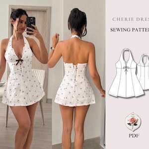 Könnte beinhalten: Ein weißes Neckholder-Kleid mit rotem Kirschmuster, tiefem V-Ausschnitt, einer dunkelroten Schleife in der Mitte und einer Schnürung am Rücken. Das Bild enthält eine technische Strichzeichnung mit der Aufschrift CHERIE DRESS SEWING PATTERN PDF.